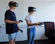 Zwei Studierende testen ein Computer Spiel mit Virtual Reality Brille und Controllern